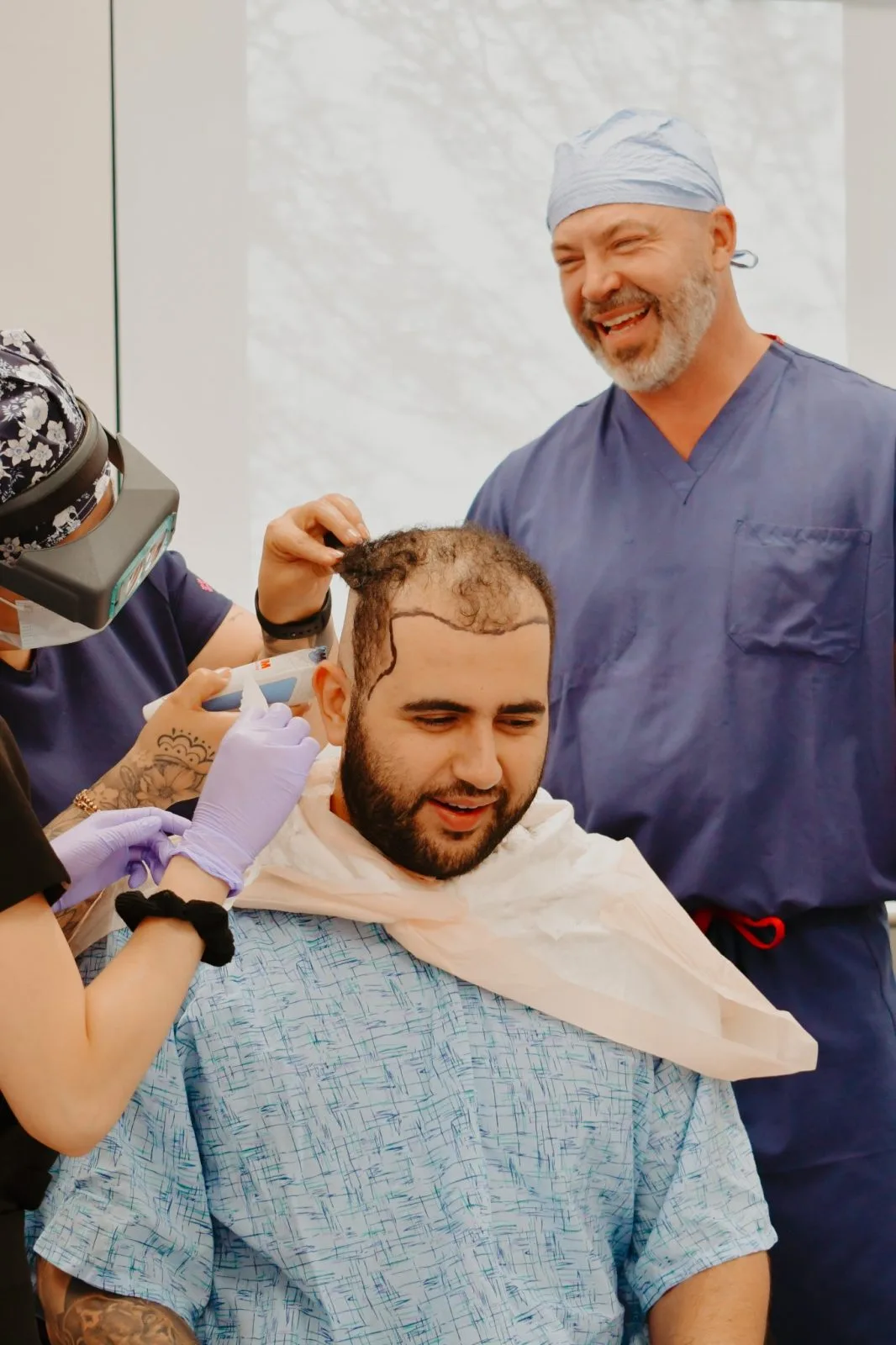 Surgeon and team member examining patient's scalp during hair restoration consultation in clinical setting